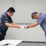 　防衛省沖縄防衛局の村井勝局長（右）に意見書を手渡す沖縄県議会・米軍基地関係特別委の小渡良太郎委員長＝２３日午前、沖縄県嘉手納町