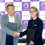 　ソフトバンクの常務執行役員（左）と握手する東北大の越村俊一教授＝２７日午後、東京都港区