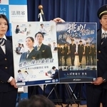 　採用案内のポスターを掲げる出入国在留管理庁の職員＝２８日午前、法務省
