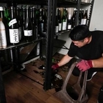 　地震の影響で割れた瓶を片付ける酒屋の店員＝２９日午後３時５０分、熊本県八代市