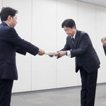 　総務省の担当者から行政指導の文書を受け取るＫＤＤＩの松田浩路社長（中央）＝２９日午後、東京都千代田区