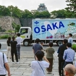 　大阪府の職員らに見送られ出発する自走式トイレカー。奥は大阪城＝２９日午後、大阪市中央区