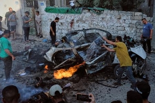 　ガザ市でイスラエル軍の攻撃後に燃えた車を消火するパレスチナ人ら＝２日（ＡＰ＝共同）