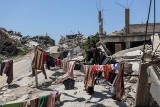 　イスラエルの攻撃で破壊された建物のがれきの中で、洗濯をするパレスチナ人避難民の女性＝３日、ガザ北部ベイトラヒヤ（ゲッティ＝共同）