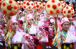　「山形花笠まつり」で紅花を模した飾り付きのかさを手に通りを練り歩く踊り手たち＝５日夕、山形市