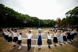 　原爆落下中心地碑を囲む「高校生平和大使」らによる「人間の鎖」＝９日午前、長崎市の爆心地公園