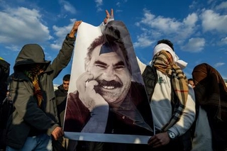 　クルド労働者党（ＰＫＫ）指導者オジャラン受刑者の写真を掲げる人たち＝２０２５年２月、トルコ南東部ディヤルバクル（ＡＰ＝共同）