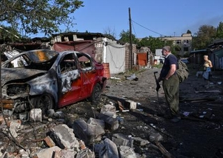 　ロシアの空爆で破壊された車を見る住民＝１１日、ウクライナ南部ザポリージャ（ロイター＝共同）