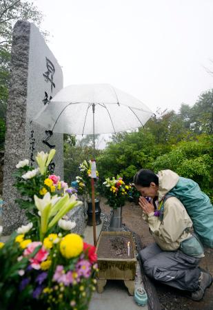 　日航機墜落事故現場の尾根に立つ「昇魂之碑」で手を合わせる人＝１２日午前、群馬県上野村