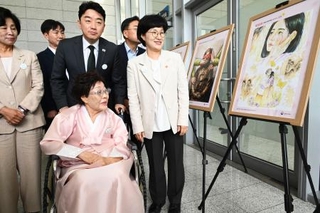 　ソウルで開かれた式典に出席し、慰安婦問題をテーマとした作品を見る元慰安婦の李容洙さん（手前）＝１４日（共同）