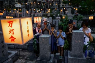 　東本願寺・大谷祖廟の「万灯会」でお参りに訪れ、手を合わせる人たち＝１４日夕、京都市東山区