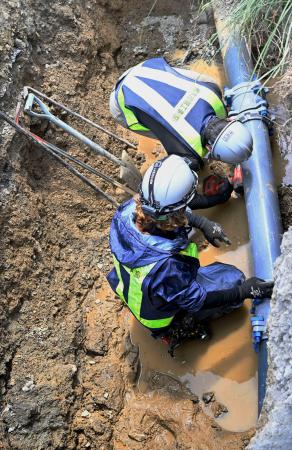　配水管の破損部分を修理する作業員＝１６日午後、熊本県八代市