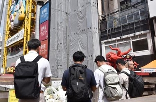 　大阪市の繁華街・道頓堀のビル火災発生から１年となり、現場付近で手を合わせる人たち＝１８日午前