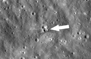 　スペースＸのロケット残骸が月面に衝突した後、ＮＡＳＡの月周回探査機が撮影した画像。中心付近（矢印）に衝突前にはなかったクレーターが確認できる（ＮＡＳＡ提供・ＡＰ＝共同）