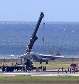 　１８日、那覇空港の滑走路で立ち往生し、クレーンで引き上げられる航空自衛隊のＦ１５戦闘機