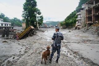 　２７日、ネパール中部で洪水が起きた現場に立つ警察官と捜索犬（ＡＰ＝共同）