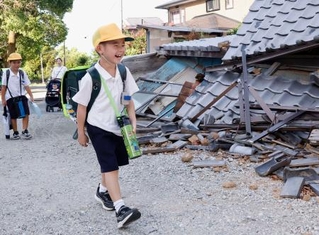 　がれきの脇を歩き、小学校の始業式に向かう児童。久しぶりの登校は楽しみだが、友達が学校にちゃんと来ているか心配しているという＝２８日午前、熊本県八代市