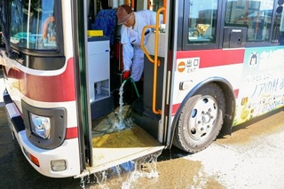 　バスの車内に入り込んだ泥を掃除する運転手の橋本昌挙さん＝３１日午前、福井県坂井市の京福バス坂井営業所