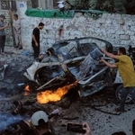 　ガザ市でイスラエル軍の攻撃後に燃えた車を消火するパレスチナ人ら＝２日（ＡＰ＝共同）