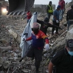 　地震で倒壊した建物から回収した遺体を運ぶ人＝７月３０日、ベネズエラ・ラグアイラ（ＡＰ＝共同）