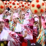 　「山形花笠まつり」で紅花を模した飾り付きのかさを手に通りを練り歩く踊り手たち＝５日夕、山形市