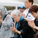 　長崎市の平和公園を訪れ、平和祈念像の前で手を合わせる人たち＝９日午後
