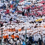 　長崎日大に勝利し、タオルを掲げる有明の応援団＝１３日、甲子園球場