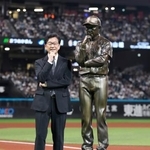 　野球殿堂入りを記念したセレモニーで、自らの立像の横で写真に納まる日本ハム前監督の栗山英樹さん＝エスコンフィールド