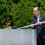 　原爆慰霊碑前の「平和の灯」から愛知・名古屋アジア大会の聖火リレーの採火をする広島市の松井一実市長＝２０日、広島市の平和記念公園