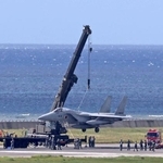 　１８日、那覇空港の滑走路で立ち往生し、クレーンで引き上げられる航空自衛隊のＦ１５戦闘機