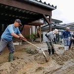 　石川県羽咋市で住宅に流れ込んだ泥を道路に出す人たち＝２８日午前