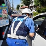 　ドライバーに生活道路の法定速度引き下げを周知する警視庁の警察官＝２５日、東京都世田谷区