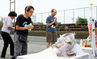 　現場となった園の駐車場で献花台に手を合わせる人たち＝５日午前、静岡県牧之原市