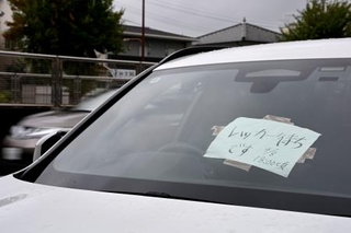 　フロントガラスに紙が張られた、大雨で被災し路上に残された車両＝９日午前９時２０分、名古屋市千種区