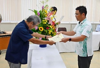 　沖縄県知事選で初当選し、当選証書を受け取る古謝玄太氏（右）＝１６日午前、沖縄県庁