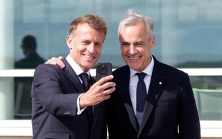 　写真を撮るカナダのカーニー首相（右）とフランスのマクロン大統領＝２０日、フランス領の群島サンピエール・ミクロン（Ａｄｒｉａｎ　Ｗｙｌｄ／カナダ通信提供・ＡＰ＝共同）