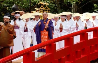 　「布橋灌頂会」で白装束とすげがさを身に着け、目隠しをして橋を渡る女性たち＝２７日午前、富山県立山町