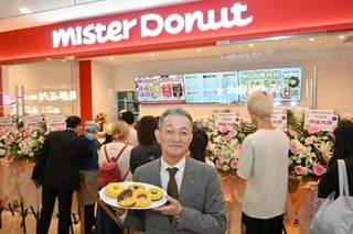 　ミスタードーナツの上海店前で商品を手にするダスキンの大久保裕行社長＝２８日（共同）
