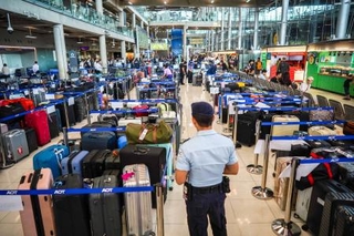 　タイ・バンコク近郊のスワンナプーム国際空港で、大量の荷物のそばに立つ警備員＝２９日（ロイター＝共同）