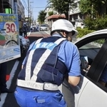 　ドライバーに生活道路の法定速度引き下げを周知する警視庁の警察官＝８月２５日、東京都世田谷区