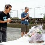 　現場となった園の駐車場で献花台に手を合わせる人たち＝５日午前、静岡県牧之原市