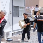 　入居が始まった仮設住宅に支援物資を運び込む有志のトラック運転手ら＝５日午前、熊本県氷川町