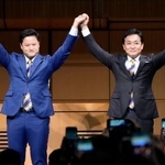 　国民民主党の代表選で３選を決め、橋本幹彦衆院議員（左）と手を取り合う玉木雄一郎代表＝６日午後、東京都千代田区