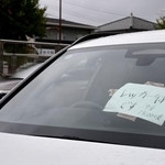 　フロントガラスに紙が張られた、大雨で被災し路上に残された車両＝９日午前９時２０分、名古屋市千種区