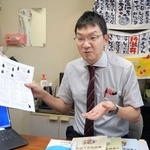 　熊本方言をまとめたパンフレットを手に取材に応じる東北大の中西太郎准教授＝８月、仙台市