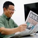 　沖縄県知事選から一夜明け、当選を伝える新聞を手にする古謝玄太氏＝１４日午前、那覇市