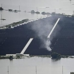 　堤防が決壊し冠水した千葉県・印旛沼の近くの太陽光発電施設から上がる煙＝２４日午前１１時、成田市（共同通信社ヘリから）