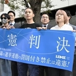 　１８歳未満の選挙運動を禁止する公選法の規定を巡る訴訟の東京地裁判決を受け「違憲判決」と記した横断幕を手にする原告ら＝２５日午後、東京地裁前