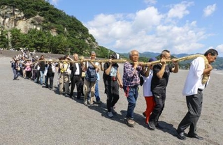 　三重県熊野市の花窟神社で営まれた「お綱かけ神事」でご神体の巨岩から大綱を引く参拝客ら＝２日午前