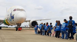 　ジェット機を綱で引っ張る児童や保護者ら＝４日午前、成田空港